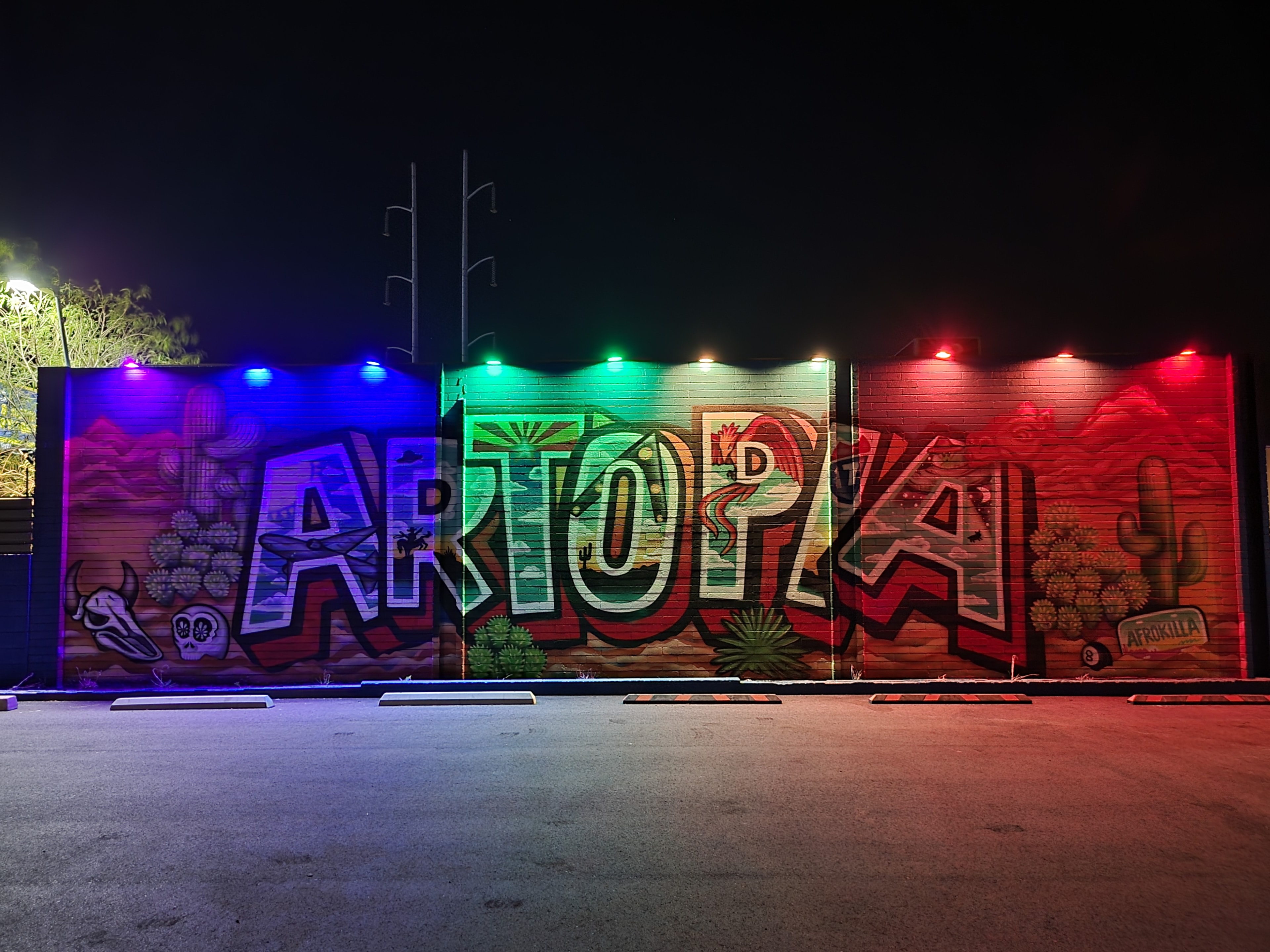 Artopia outdoor mural lit with blue, green, and red lights at night
