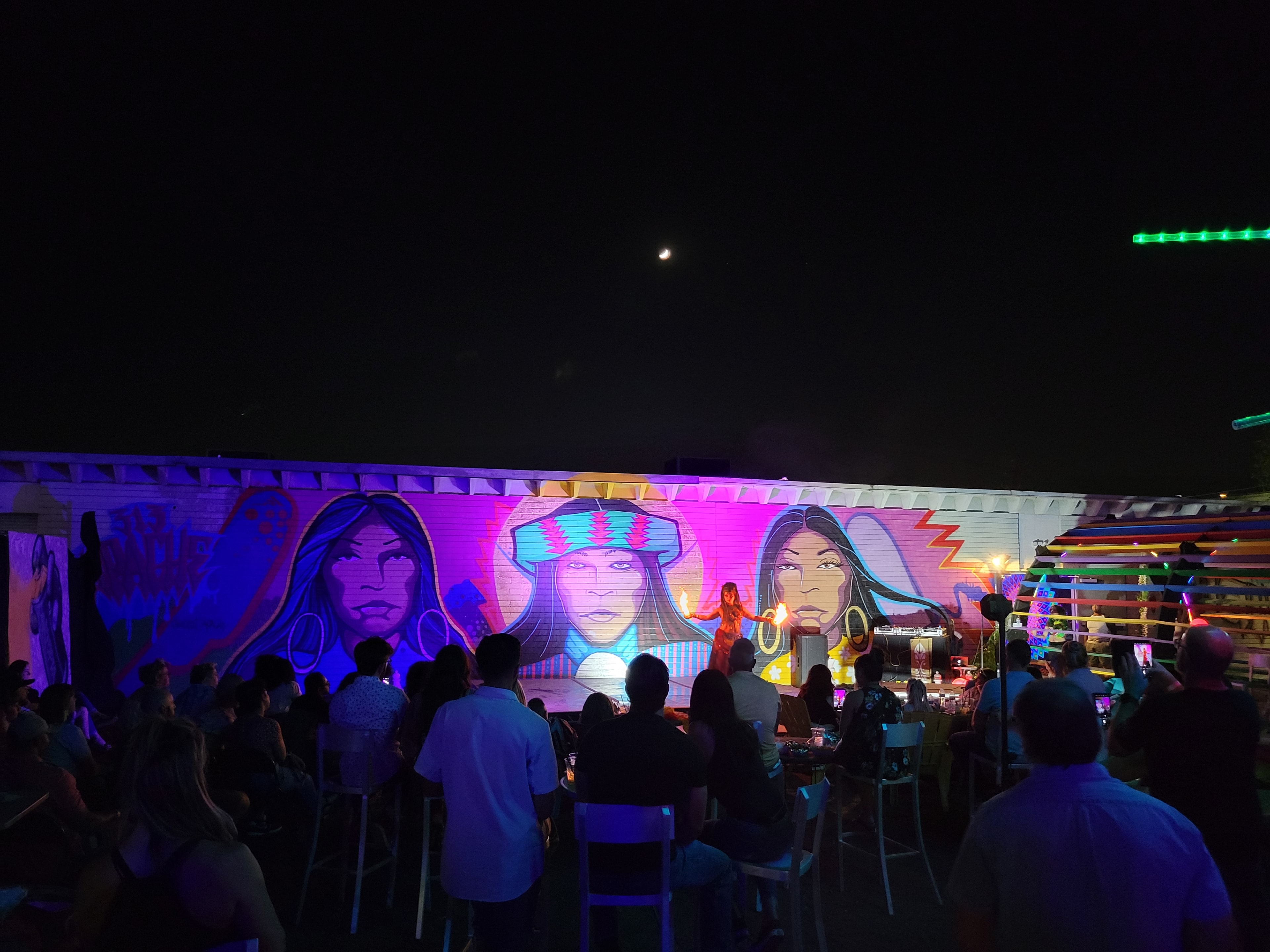 Artopia outdoor night event with fire performer and neon mural portraits