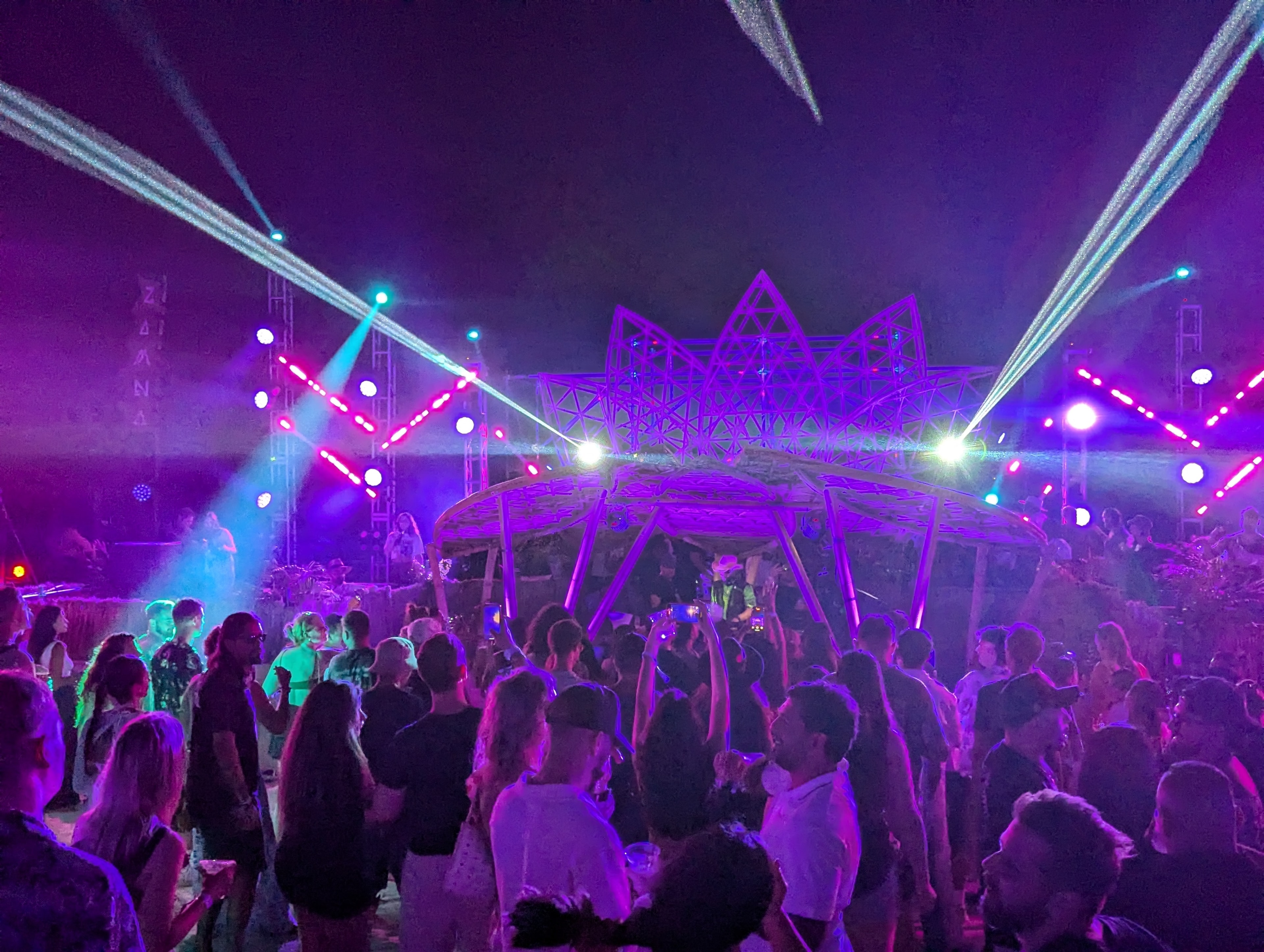 Outdoor stage with geometric sculpture and laser beams at Destination Unknown