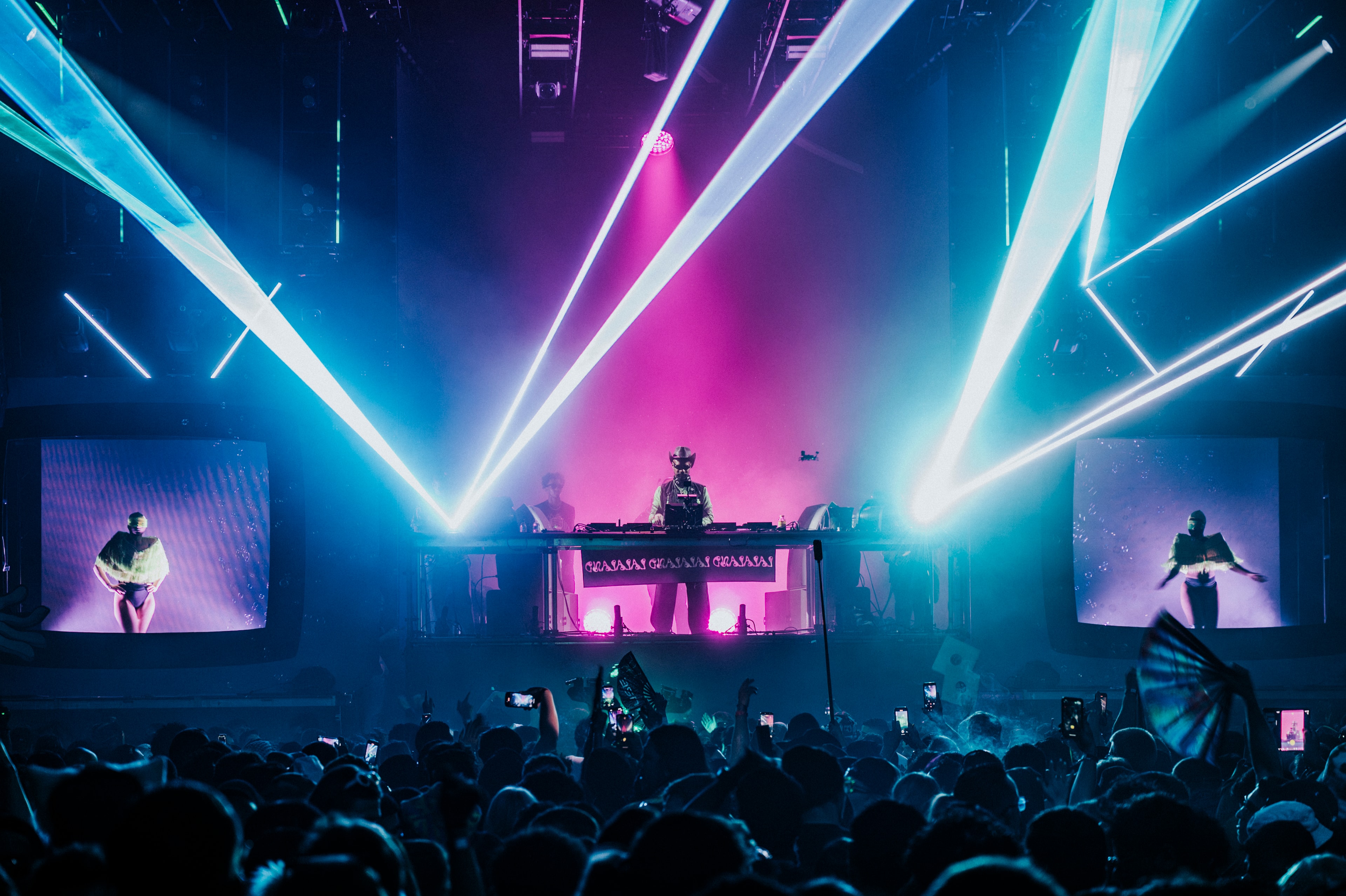 La La Land stage — cyan and magenta laser show with DJ silhouette and side screens